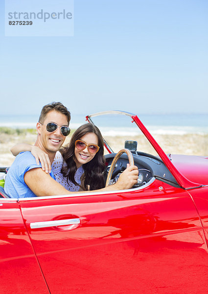 Paarfahrendes Cabrio am Strand