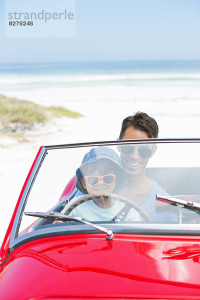 Vater und Sohn fahren Cabrio am Strand