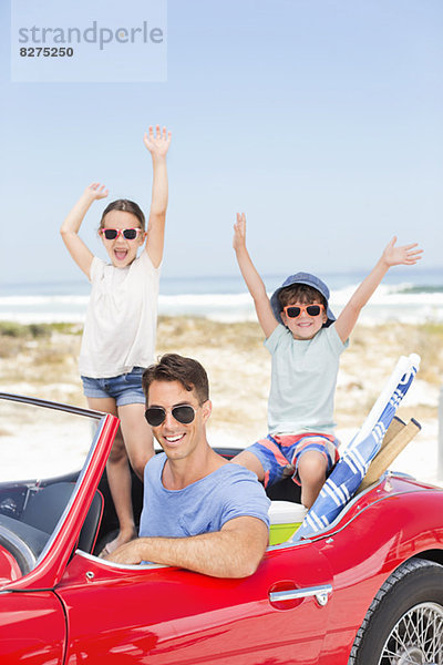 Vater und Kinder im Cabrio am Strand