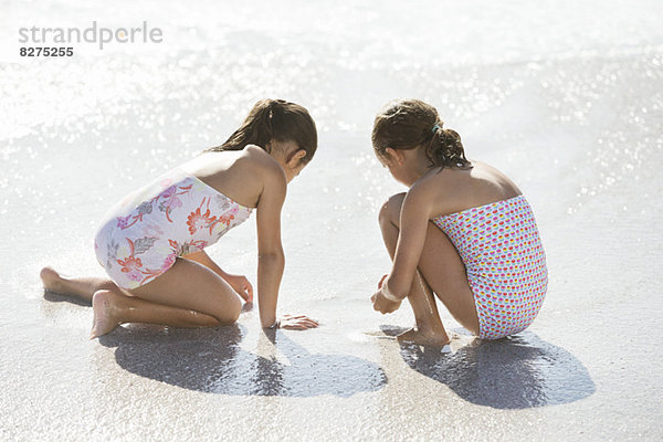 Mädchen beim gemeinsamen Surfen am Strand