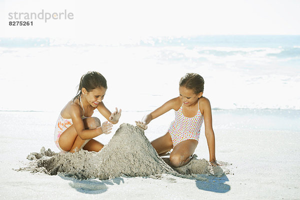 Mädchen bauen Sandburg am Strand