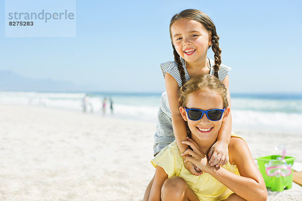 Porträt von lächelnden Mädchen  die sich am Strand umarmen