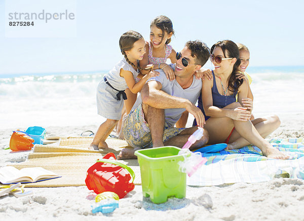 Familienumarmung auf der Decke am Strand