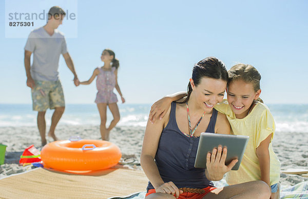 Mutter und Tochter mit digitalem Tablett am Strand