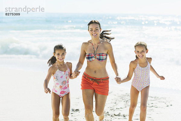 Mutter und Töchter beim Händchenhalten und Laufen am Strand