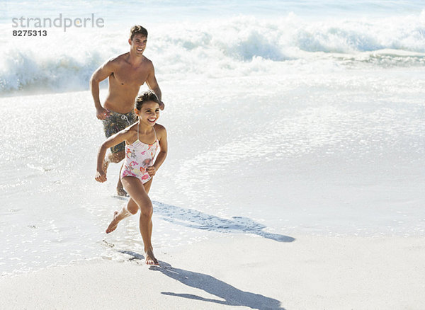 Vater und Tochter beim Surfen am Strand