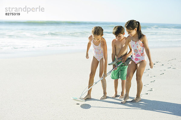 Kinder mit Metalldetektor am Strand