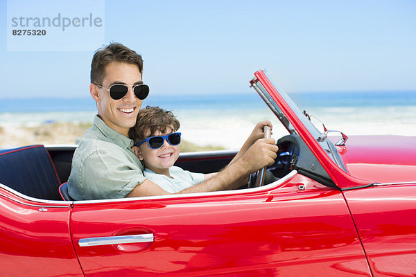 Vater und Sohn fahren Cabrio am Strand