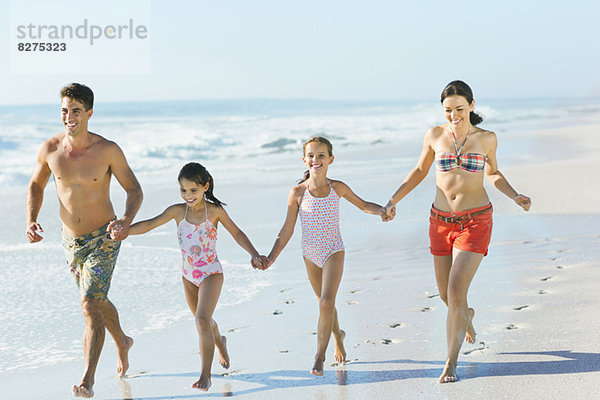 Familie beim Händchenhalten und Laufen am Strand