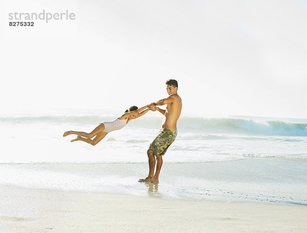 Vater schwingende Tochter am Strand