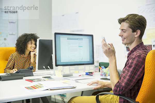 Geschäftsmann mit Handy am Schreibtisch im Büro