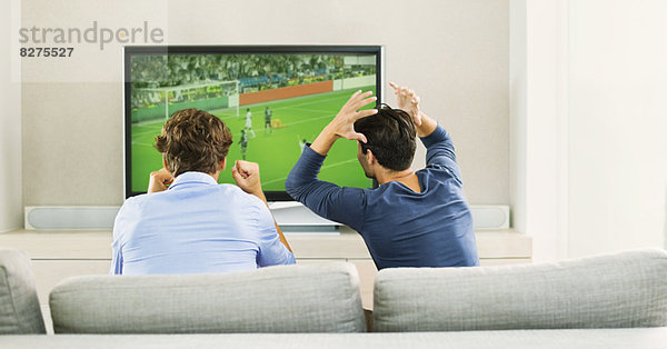 Männer beim Fußball schauen auf dem Sofa