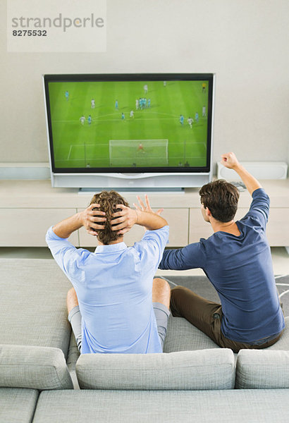 Männer beim Fußball schauen auf dem Sofa