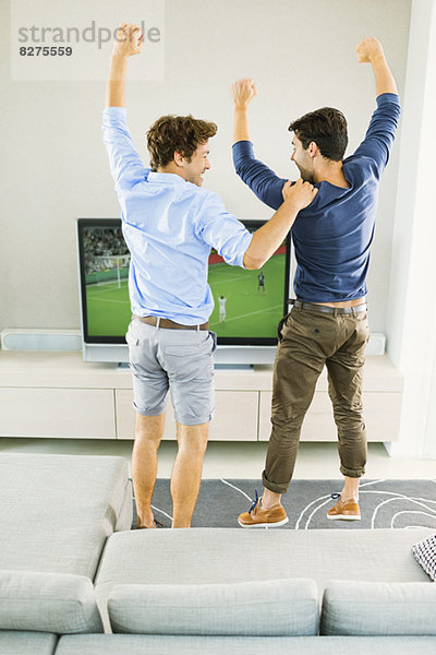Männer jubeln und schauen Fußballspiel
