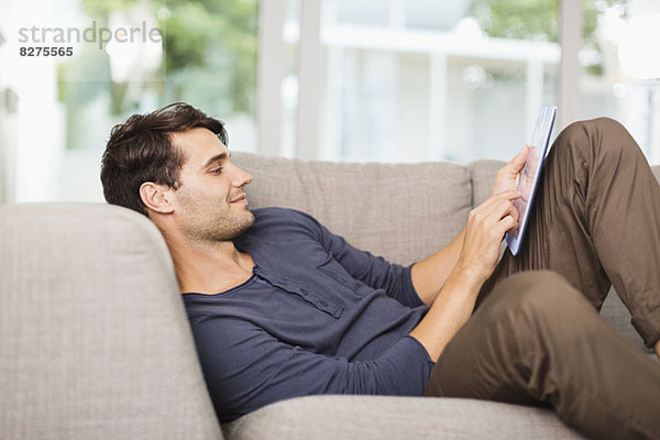Mann mit digitalem Tablett auf dem Sofa
