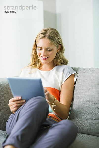 Frau mit digitalem Tablett auf dem Sofa