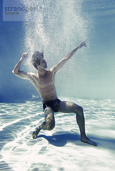 Mann posiert unter Wasser im Schwimmbad