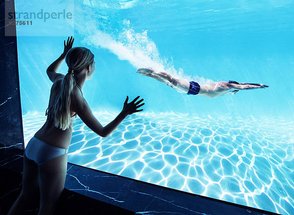 Frau beobachtet Freund unter Wasser im Schwimmbad