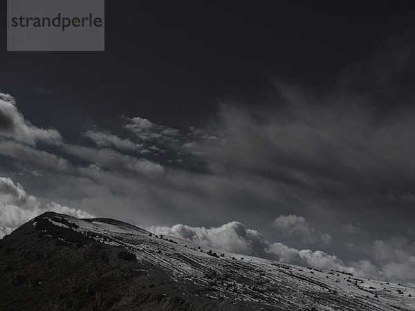 Ein dramatisch bewölkter Himmel über dem schneebedeckten Berg