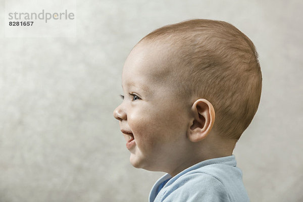Ein sorgloses Baby  das lächelt und lacht  während es aus der Kamera schaut.