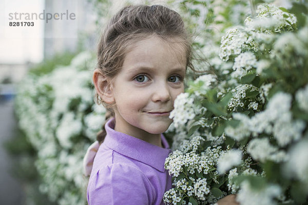 Ein junges Mädchen  das Blumen riecht.