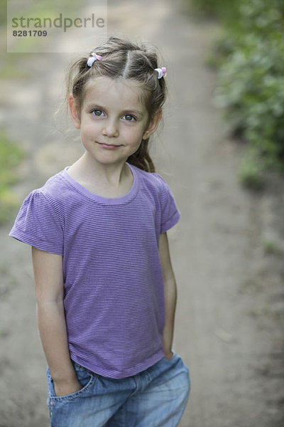Ein junges lächelndes Mädchen  das auf einem Feldweg steht.