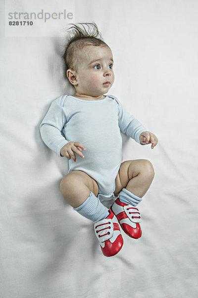 Ein kleiner Junge  der Fußballschuhe trägt und nachdenklich aussieht.