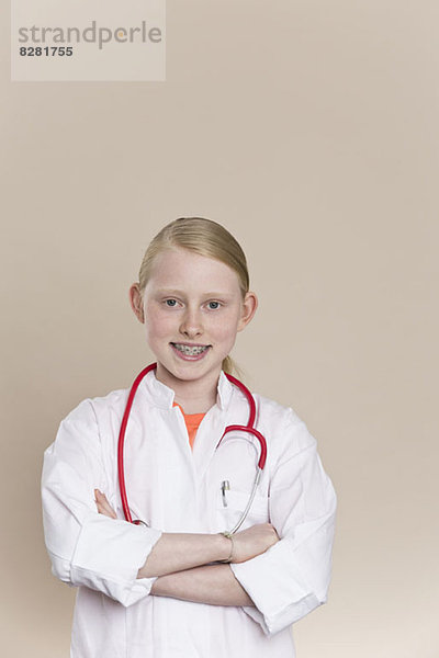 Ein lächelndes Mädchen in einem Laborkittel mit einem Stethoskop um den Hals.