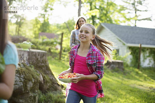 Biologische Landwirtschaft. Sommerfest. Drei Mädchen rennen über das Gras.