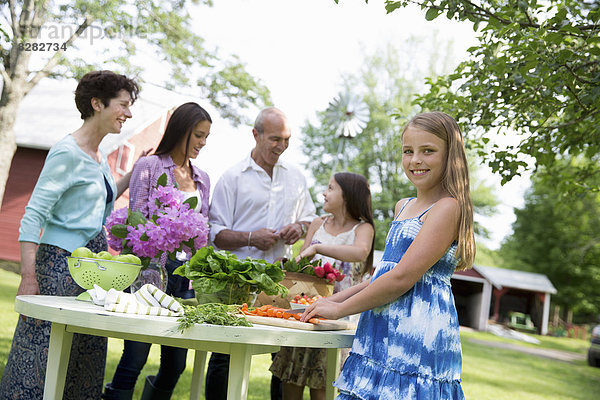 Familienfeier. Ein gedeckter Tisch mit Salaten und frischem Obst und Gemüse. Eltern und Kinder. Zwei Mädchen  eine junge Frau und ein reifes Paar.