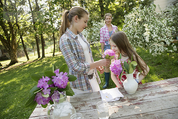 Drei Menschen sammeln Blumen und arrangieren sie gemeinsam. Eine reife Frau  ein Teenager und ein Kind.