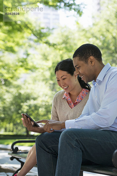 Sommer. Geschäftsleute. Ein Mann und eine Frau sitzen mit einem digitalen Tablet und bleiben in Kontakt.
