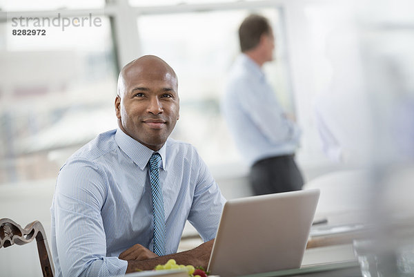 Büroleben. Geschäftsmann in Hemd und Krawatte am Schreibtisch sitzend  mit einem Laptop-Computer.