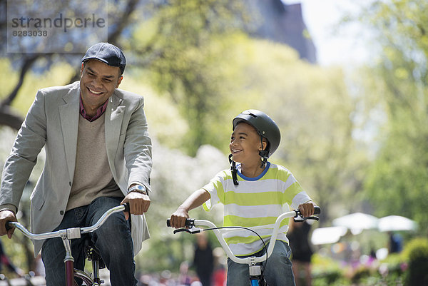 Eine Familie im Park an einem sonnigen Tag. Vater und Sohn beim Radfahren