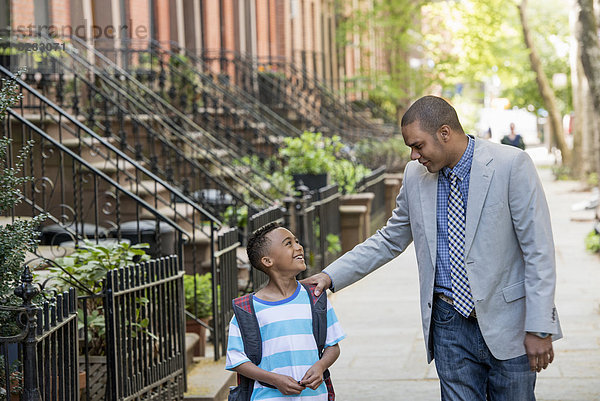 Ein Erwachsener und ein Kind  ein Vater und ein Sohn  die zusammen auf der Straße in der Stadt spazieren gehen.