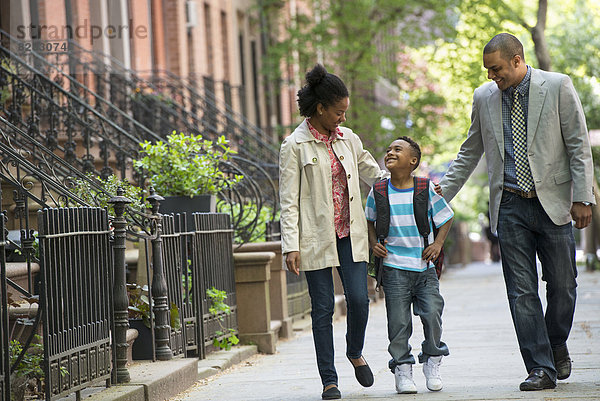 Eine Familie im Freien in der Stadt. Zwei Eltern und ein junger Junge gehen zusammen spazieren.
