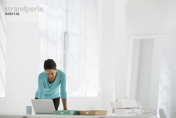 Wirtschaft. Eine Frau lehnt über einen Schreibtisch mit einem Laptop-Computer.