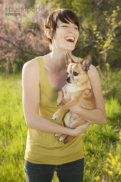 Junge Frau im Frühling auf grasbewachsenem Feld mit einem Hund