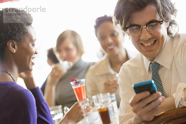 Stadtleben. Eine Gruppe von Menschen in einem CafÈ  die ihre Smartphones überprüfen.