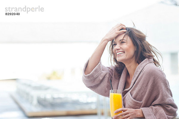 Frau im Hotel am Pool mit einem Glas Orangensaft