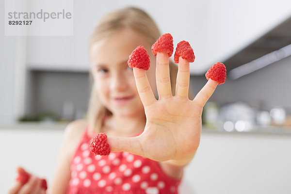 Mädchen legt Himbeeren auf die Finger