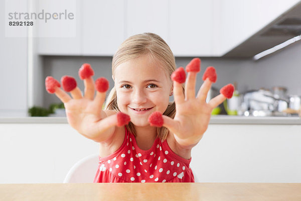 Mädchen legt Himbeeren auf die Finger