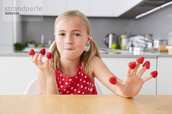 Mädchen isst Himbeeren aus den Fingern