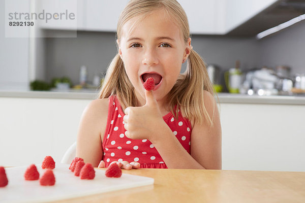 Mädchen essen Himbeeren vom Daumen