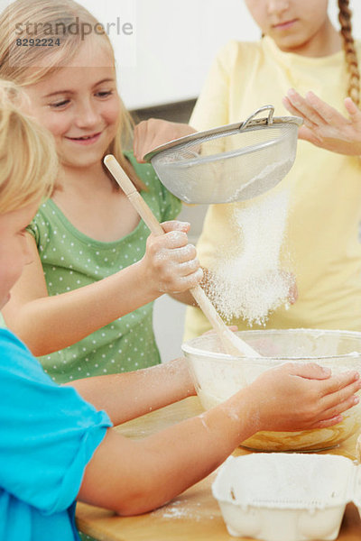 Kinder backen  Mehl in Rührschüssel sieben