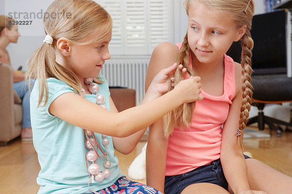 Mädchen  das die Haare der Schwester geflochten hat.