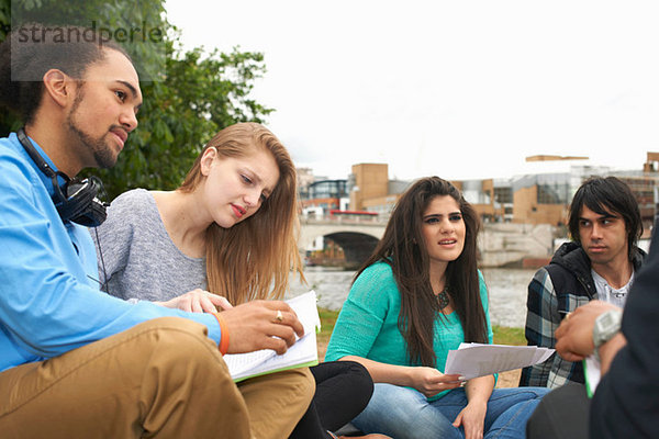 Studenten sitzen im Freien mit Papieren