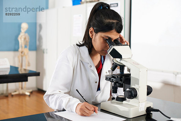 Chemiestudent mit Mikroskop im Labor