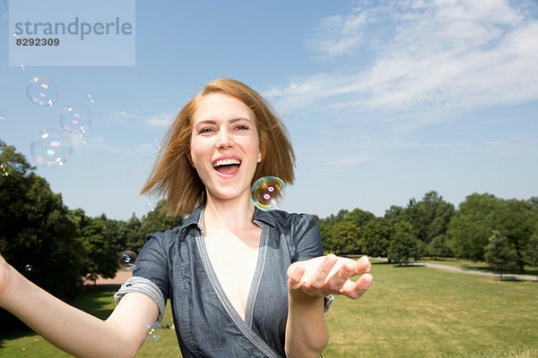 Junge Frau hat Spaß mit Blasen im Park