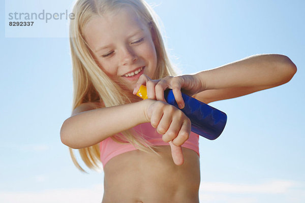 Mädchen sprühen Sonnencreme auf der Hand